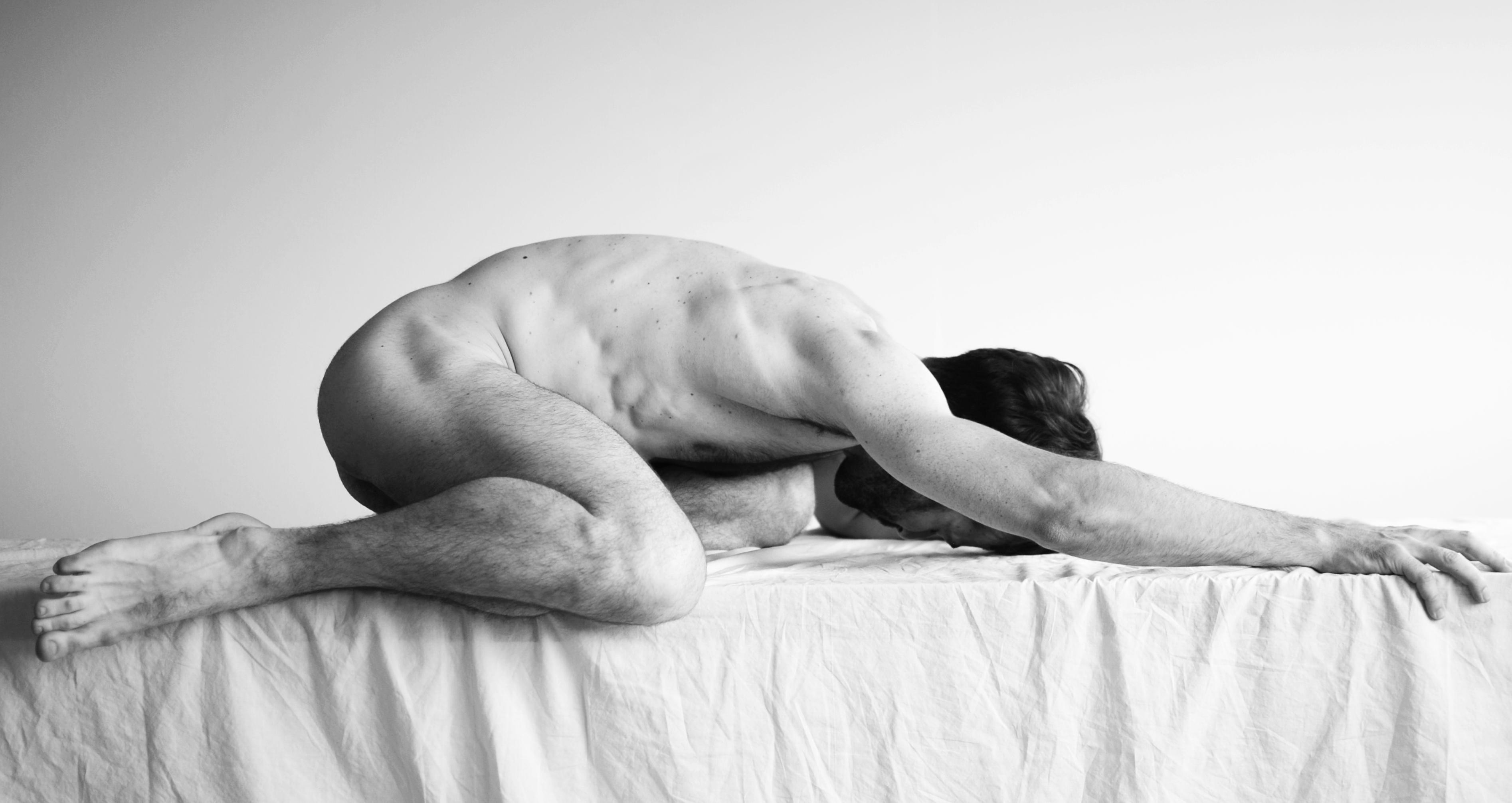 This image shows a person in a yoga-like pose on a surface. They are lying face down with their arms extended forward. It's in black and white.