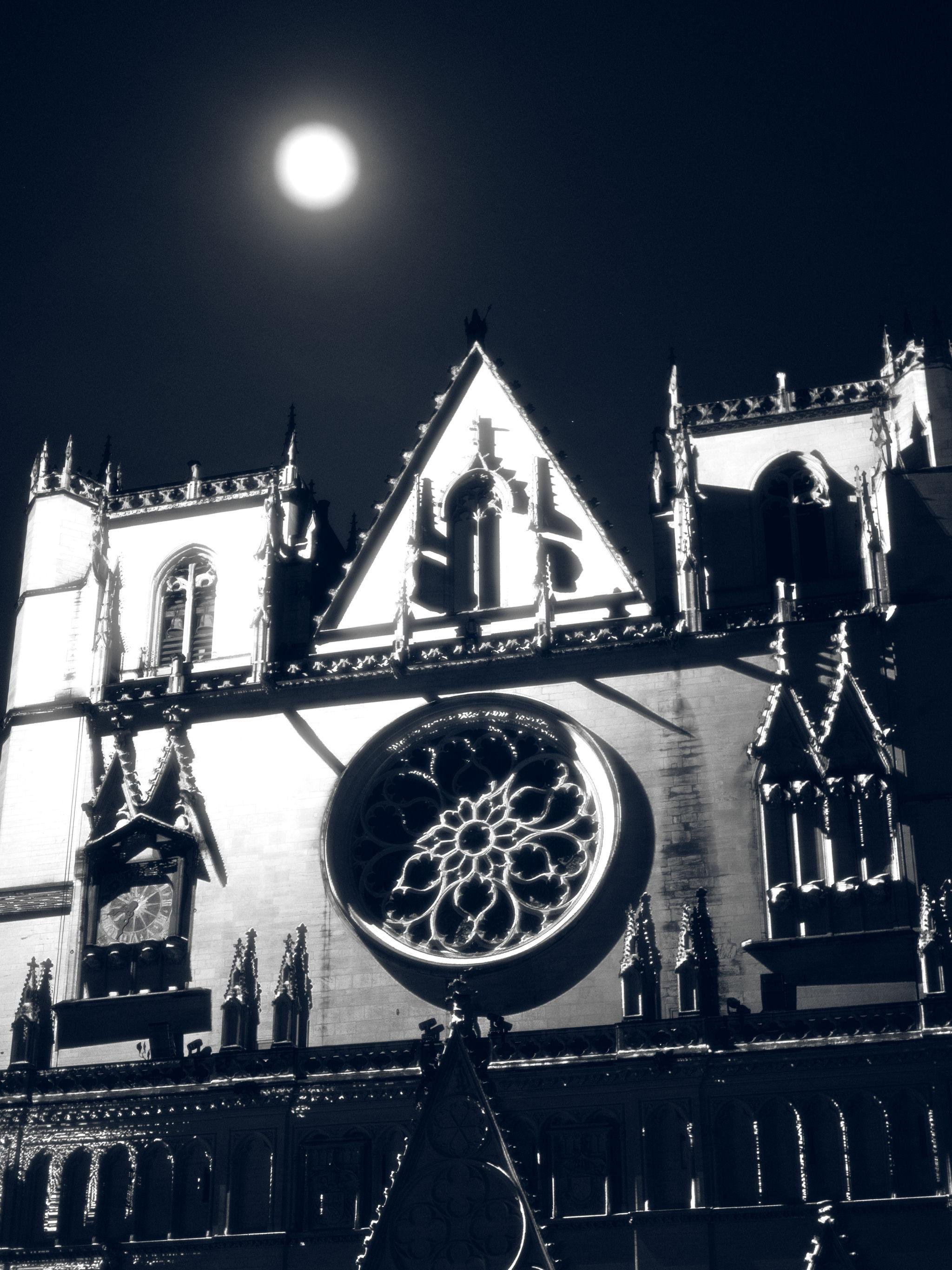 The facade of Saint-Jean cathedral in Lyon during the Fête des Lumières event. The dramatic lighting with the full moon above makes it look like the Moon is shining on the cathedral, even though the viewing angle of the scene makes it clear it's impossible.