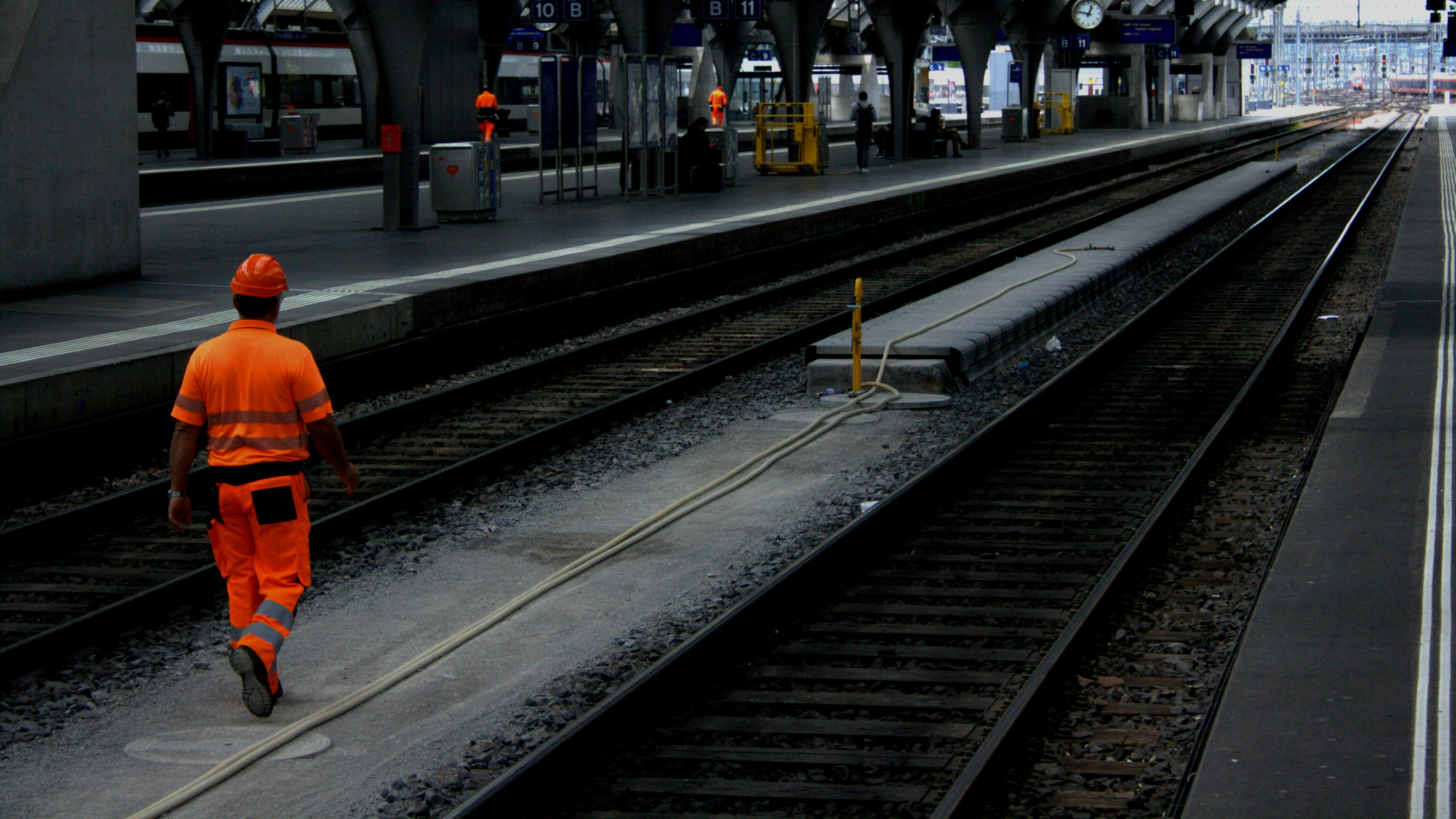 a photo of a worker in highvis gear walking down the maintenance and service platform inside of a train station