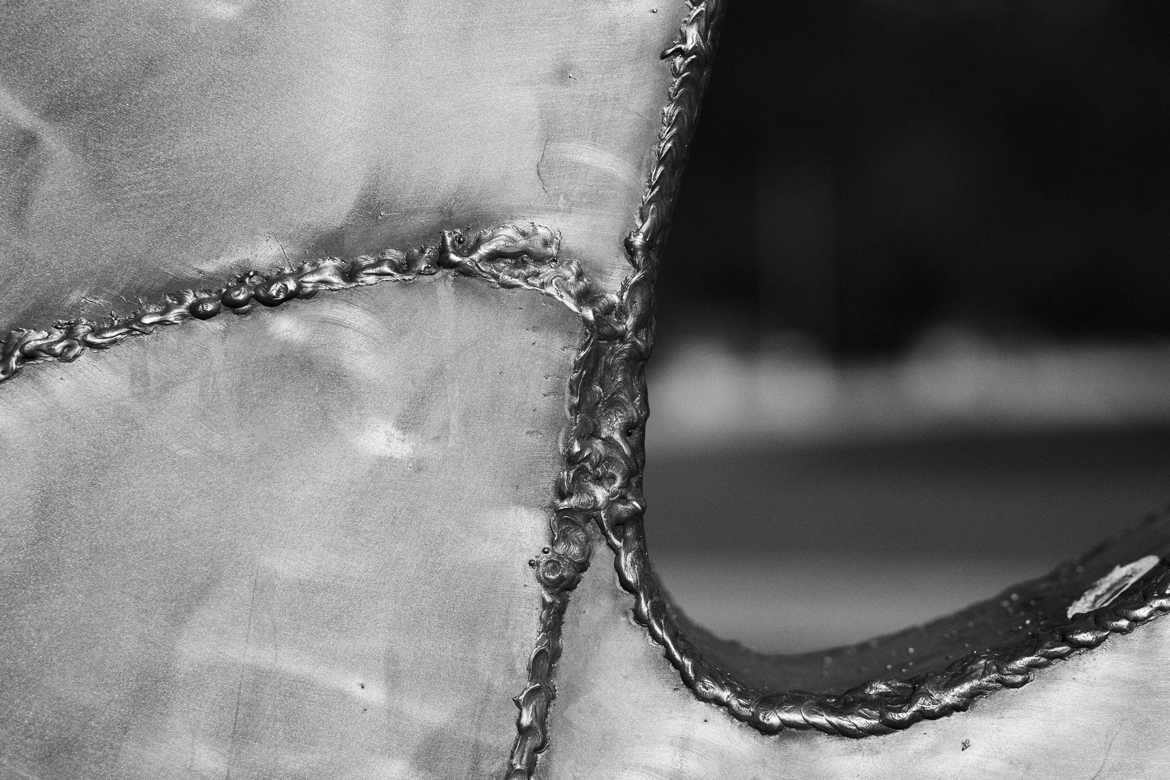 This is an image of a welded metal surface. It shows several weld seams, which appear rugged and textured. The image is in black and white, highlighting the contours and details of the welding work.