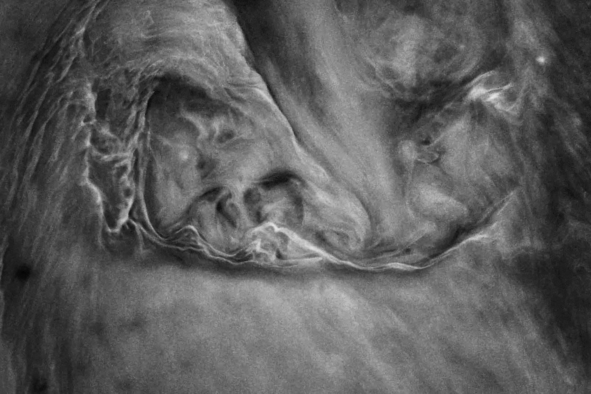 A black-and-white close-up of swirling water in a muddy puddle. In the center, two face-like outlines are formed, with fine strands and soft color gradients against a dark background.