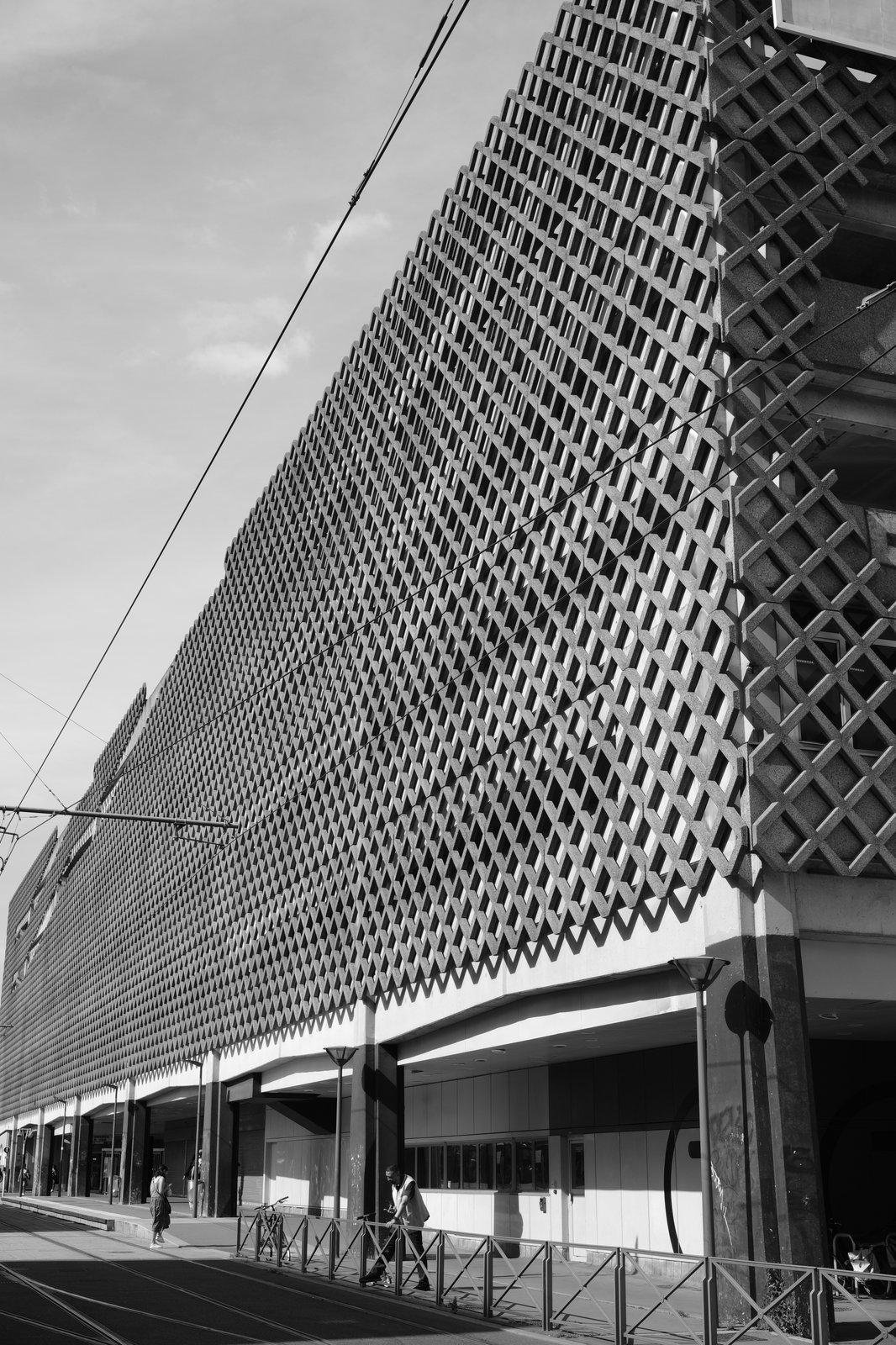 A black and white photo of a building with a wooden front with a mesh pattern