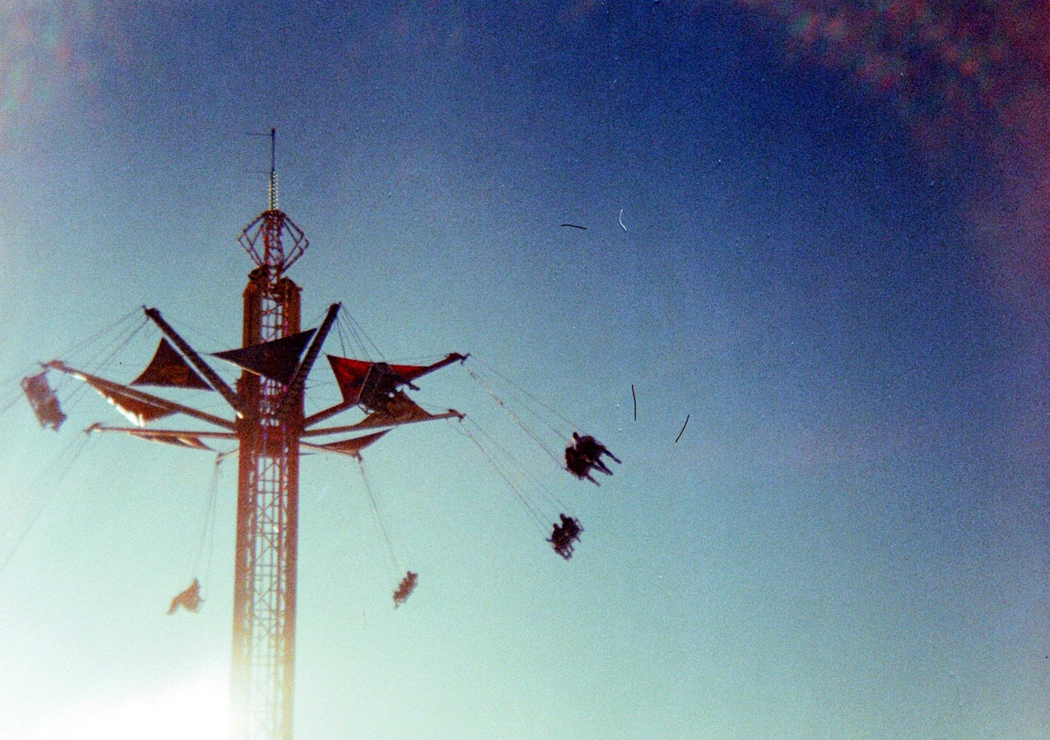 Colour scan of a 35 mm. shot.

Attraction at a local amusement park. Four swings, each holding two people, spin around a 50-metre tall tower. 

#EOS630 #iso800 #canada #quebec #35mm