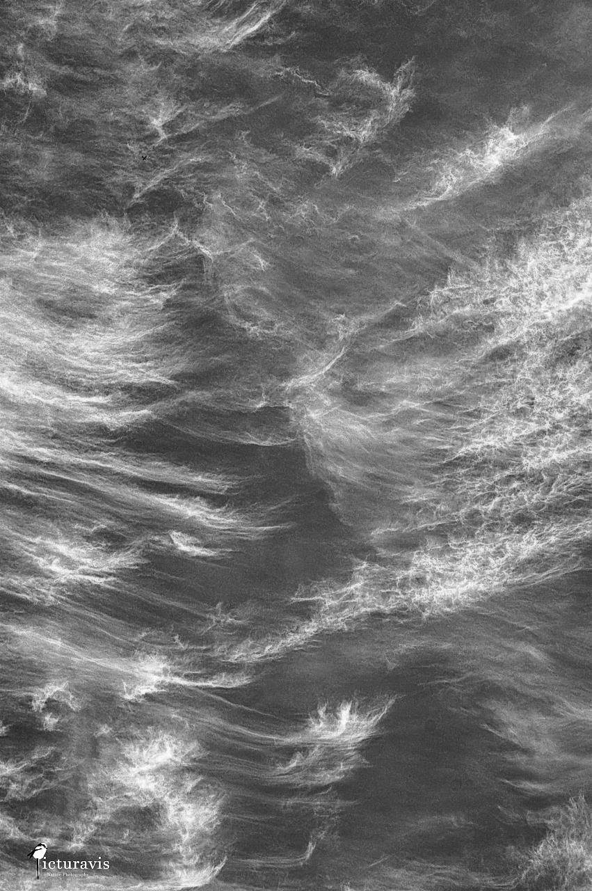 A black and white image of the sky with high-altitude clouds. Many fine details strands can be seen of the wispy cirrus clouds.