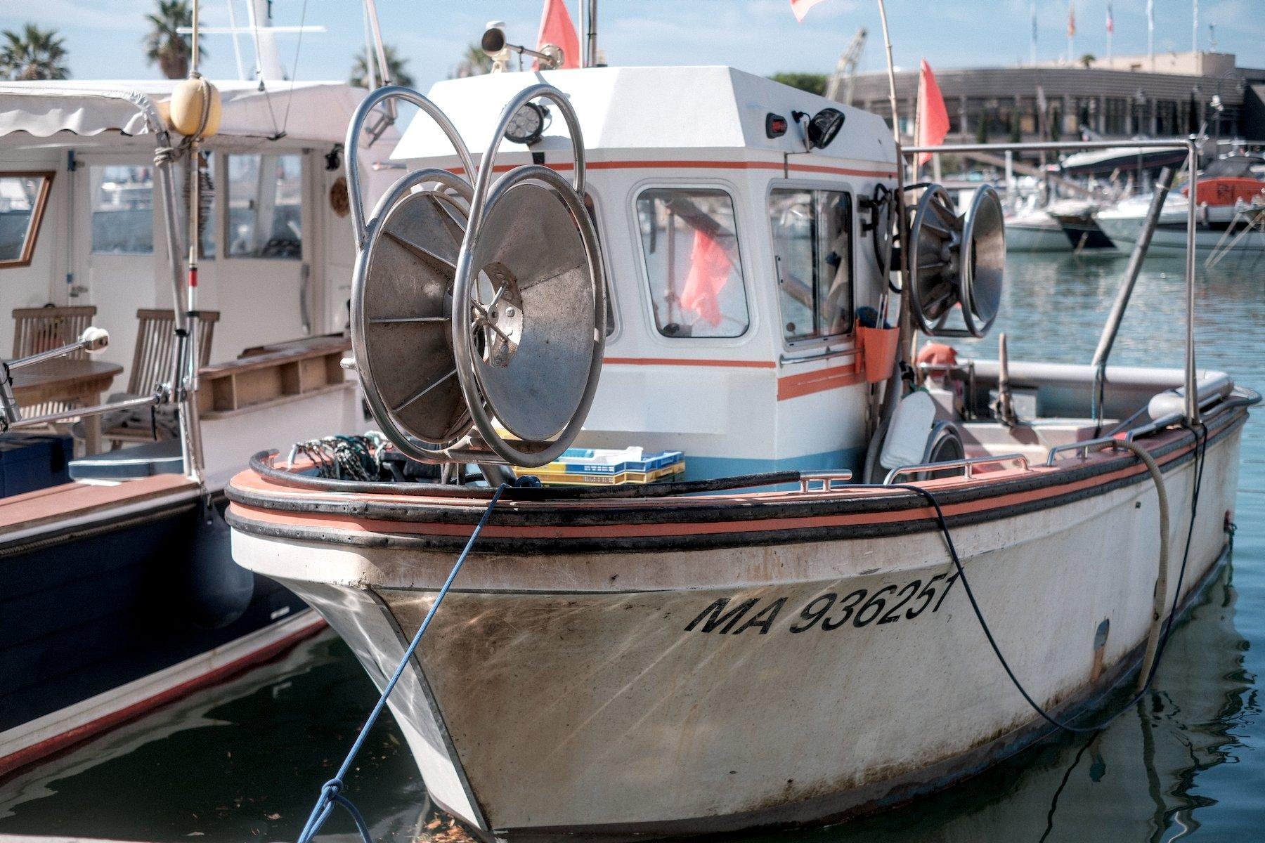 Horizontal photo. A smash fishing boat, from the front, with a wheeled shape steel device on it which must be for pulling the fish net back