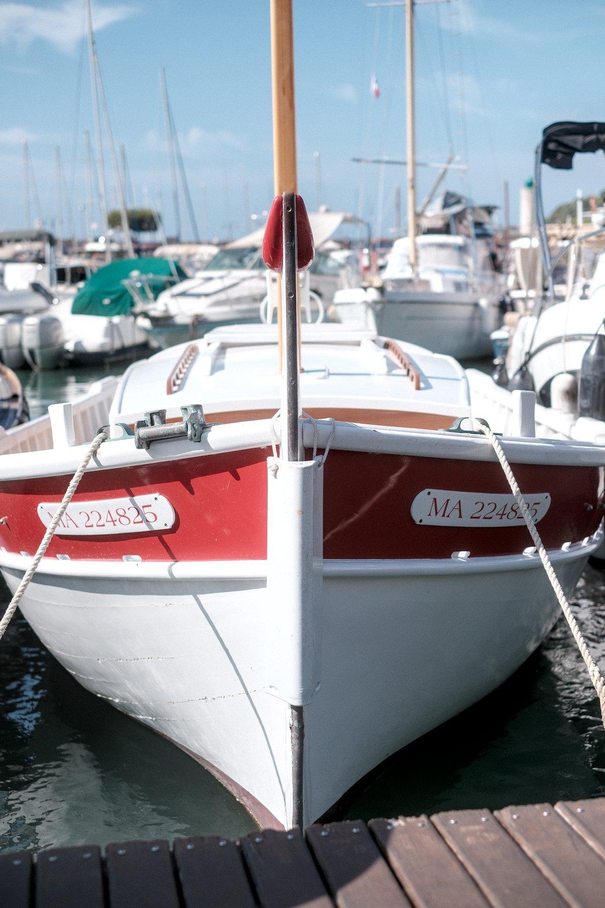 Photo verticale. Vue de face d’un petit bateau blanc avec des accents rouge