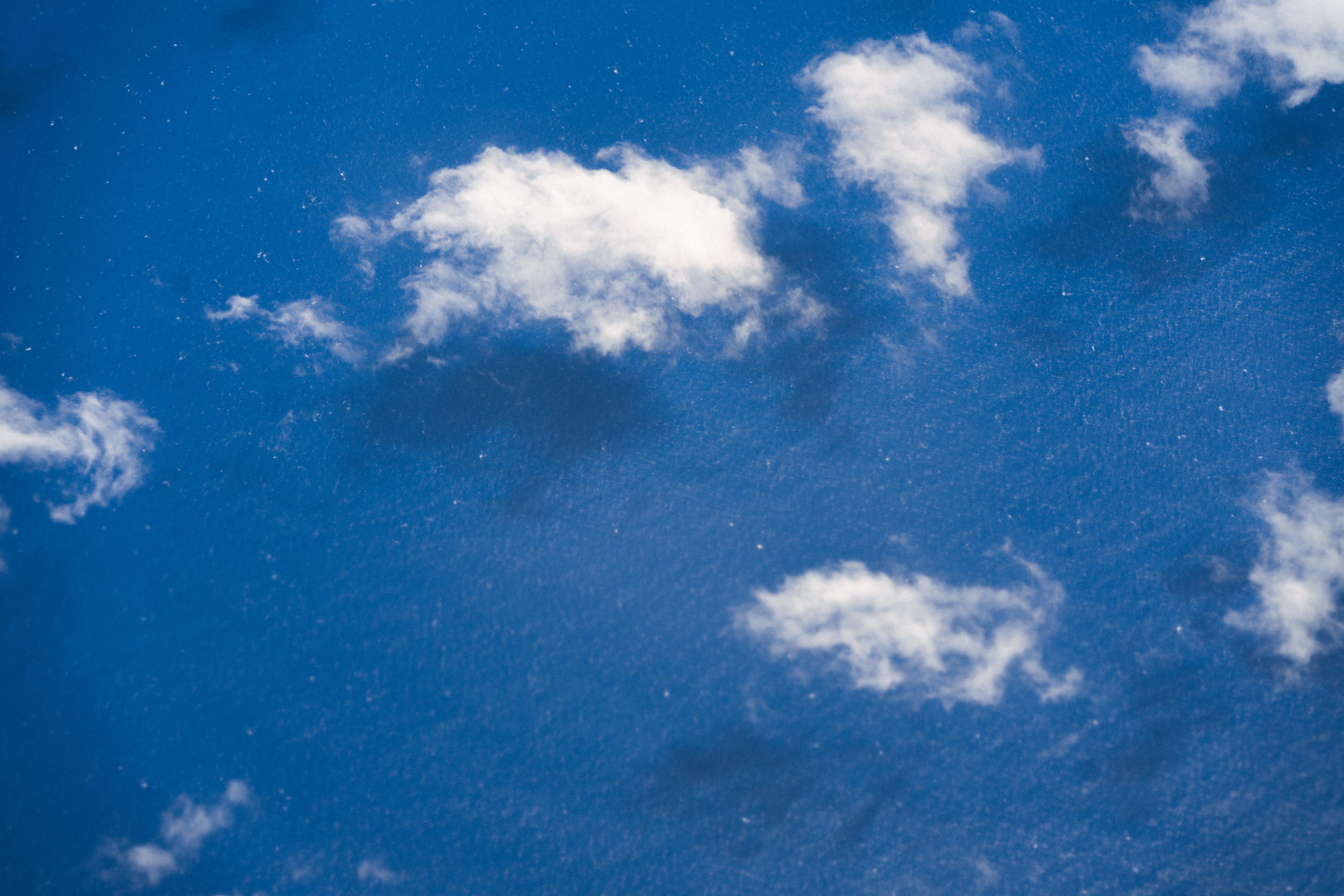 White clouds scattered across a deep blue sky, with some areas of light and shadow creating texture and depth.