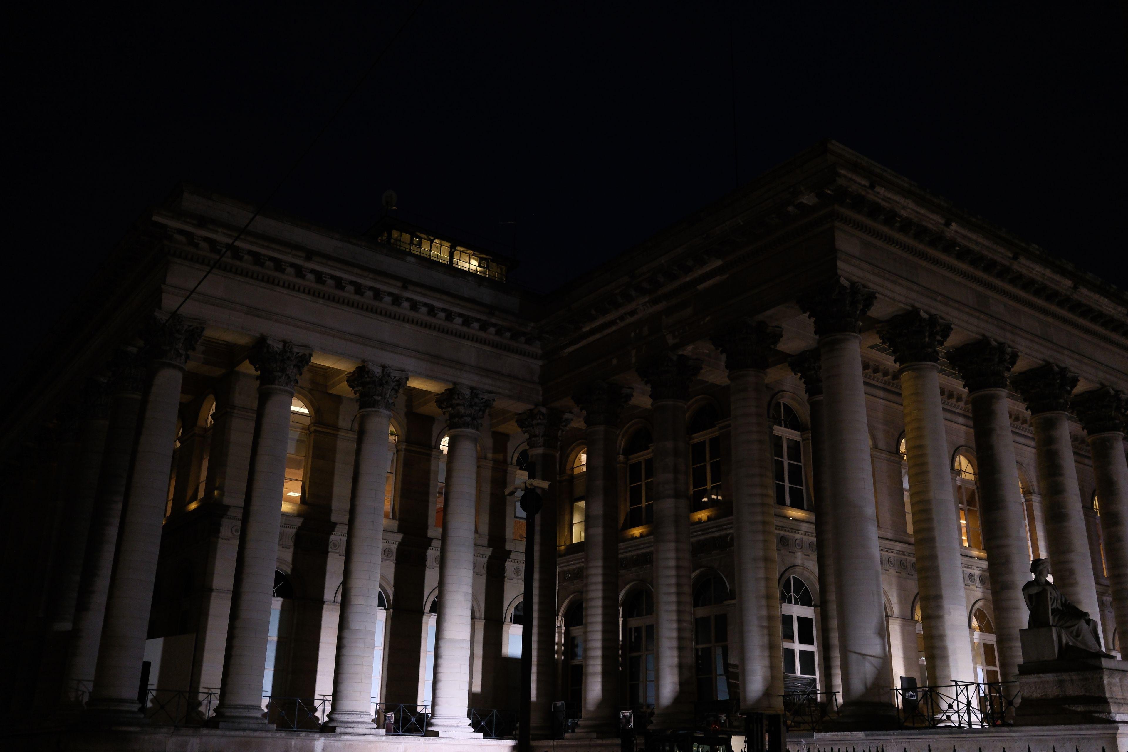 Photo horizontale de nuit. L’angle d’un grand bâtiment plein de colonnes éclairées par le bas