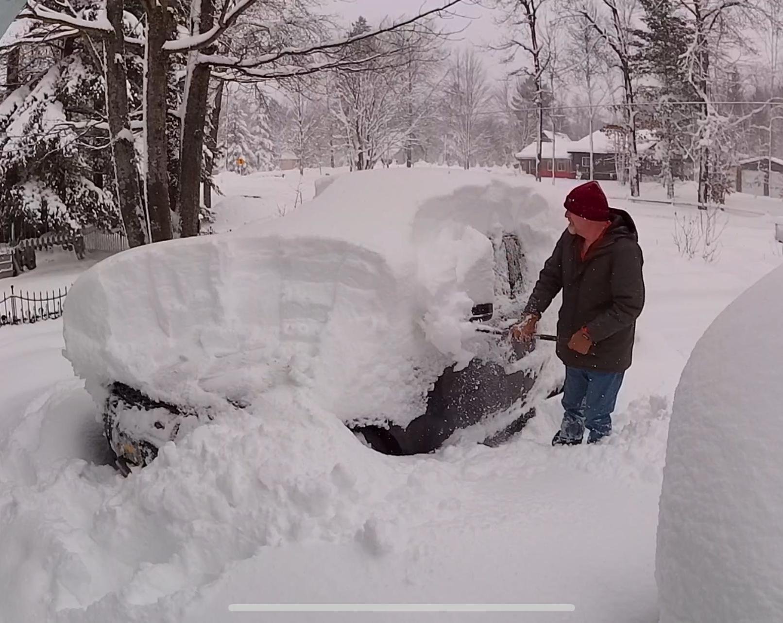 Old man digging his car out of a recent snowstorm.