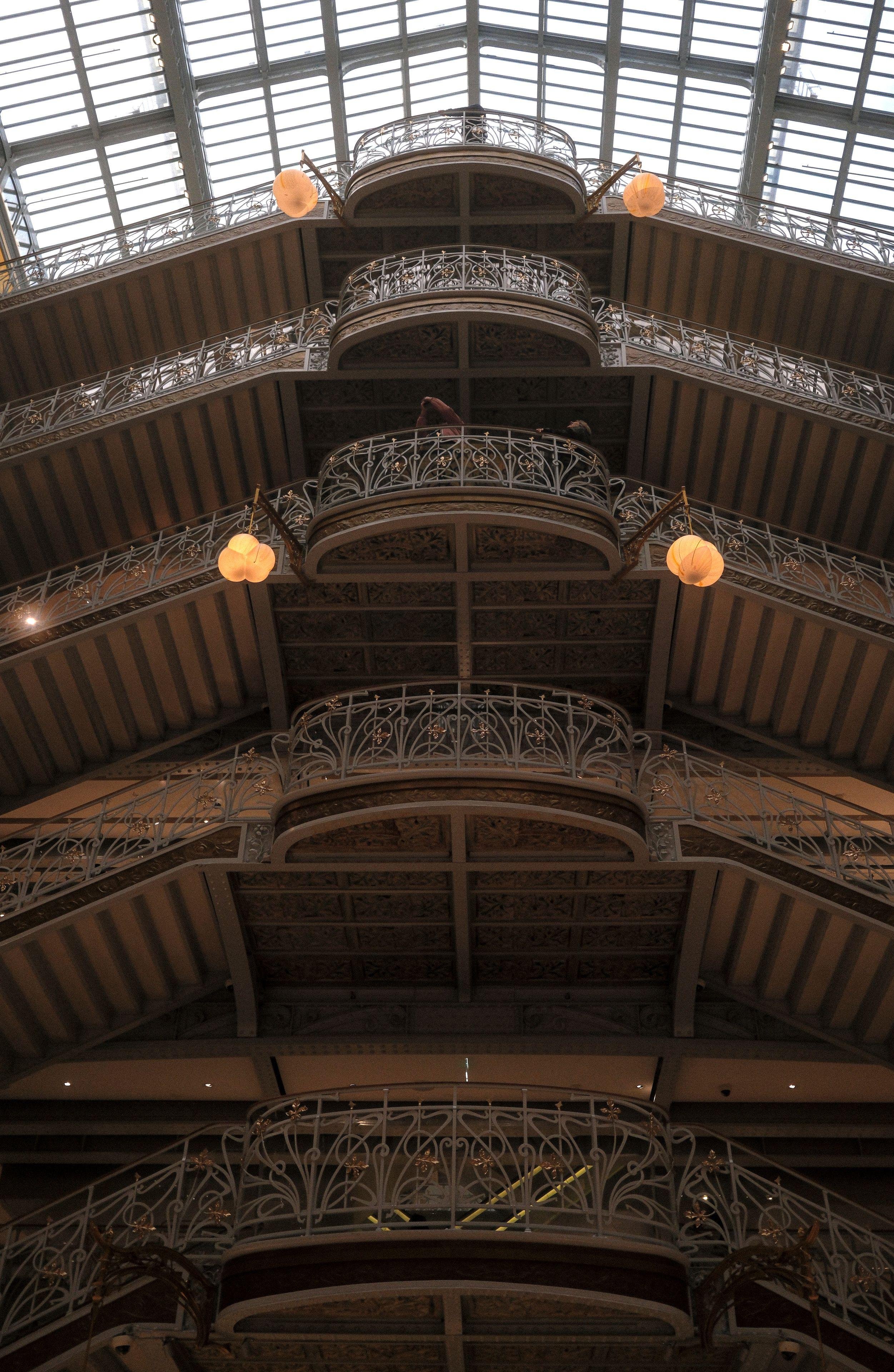 Photo verticale. Des paliers successifs de double escaliers et une verrière au dessus du dernier palier