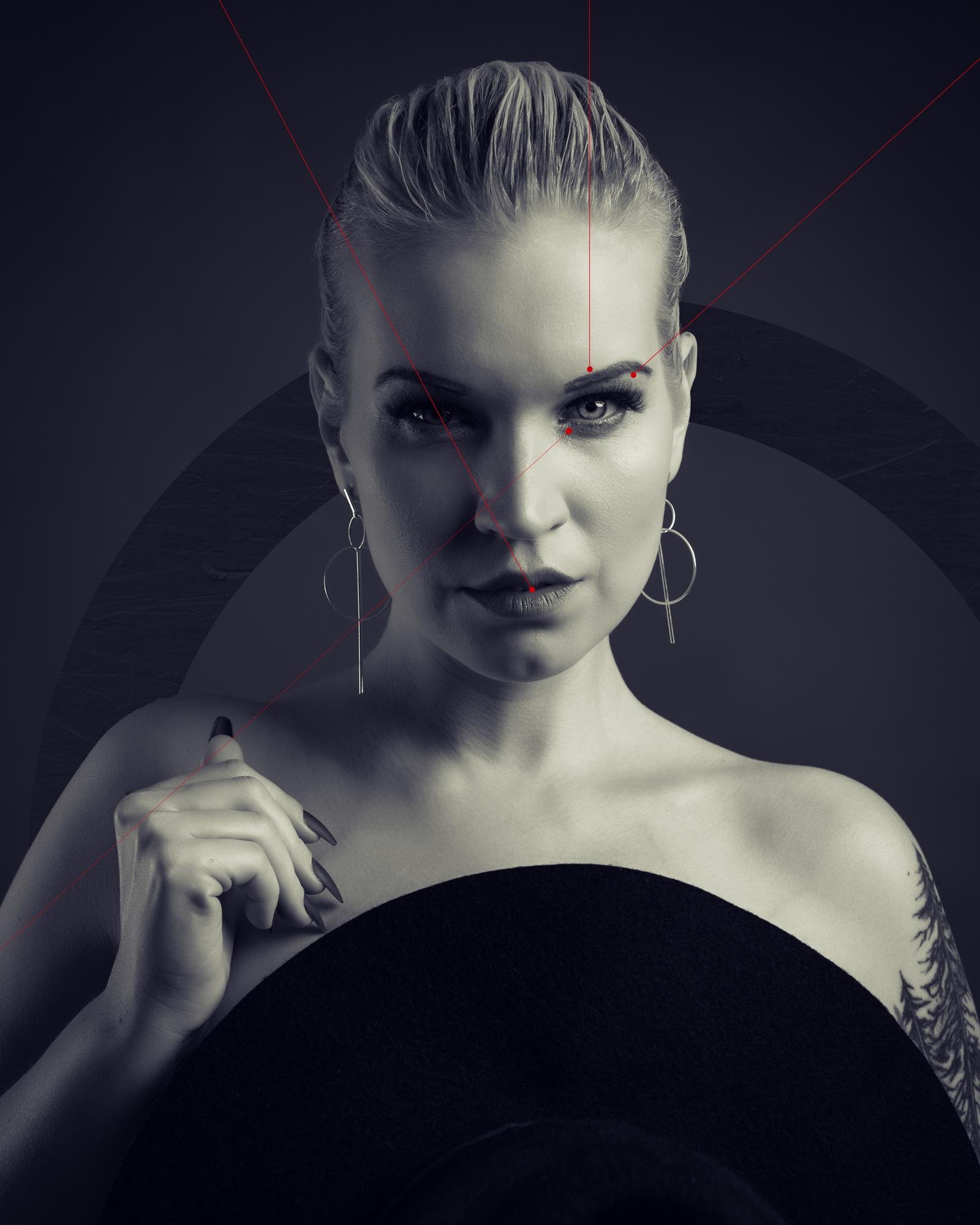 The image is a black and white portrait of a person with a serious expression. They have their hair slicked back and are wearing large hoop earrings. They appear to be holding a round object, possibly a hat. The image features some red lines and geometric designs for artistic effect.